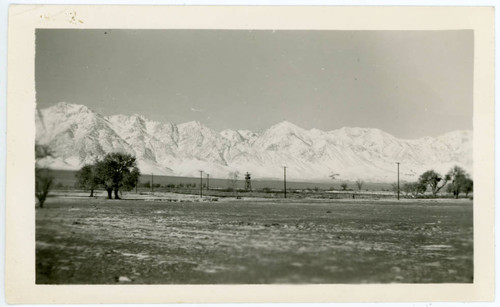 Photograph of Manzanar with snow on the ground and guard tower in the background