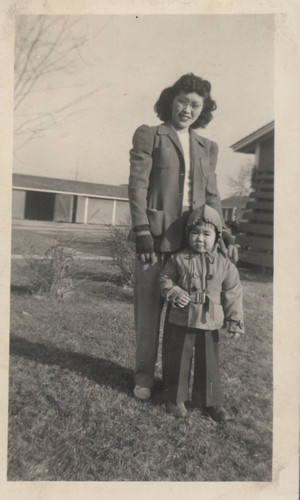 Woman and child of Japanese descent wearing jackets outside at Poston incarceration camp