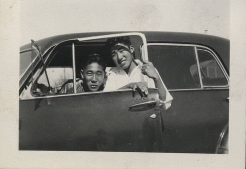 Two men look out the driver's side window of a car at Poston incarceration camp