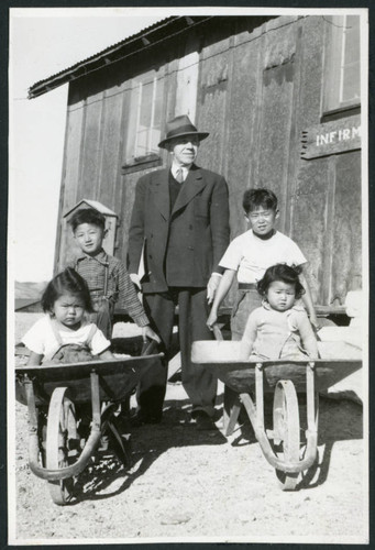 Photograph of B.R. Chamberlain, Ned and Harry Morioka and two other children posing in front of the infirmary at Cow Creek Camp in Death Valley