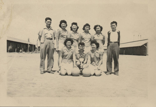 Women's' sports team pose with coaches and trophy at Poston incarceration camp