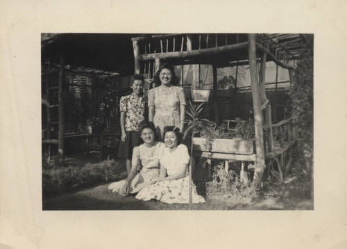 Four young woman in front of wooden garden bower structure at Poston incarceration camp