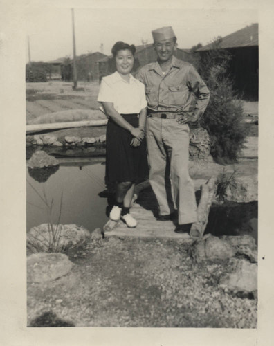 Mitsuru Yagura and woman on wooden footbridge over water at Poston incarceration camp