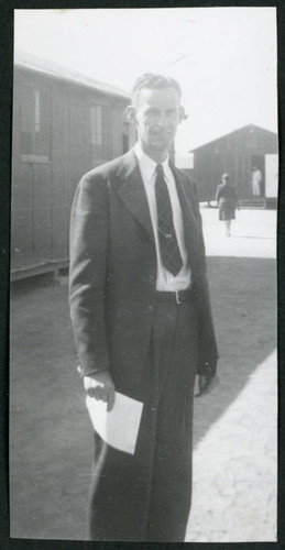 Photograph of Clyde Simpson standing in front of barracks