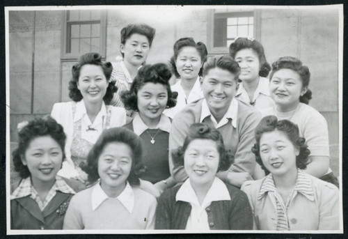 Photograph of people posing in front of a building at Manzanar