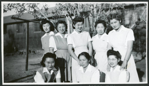 Photograph of eight hospital staff aides posing in front of the Manzanar hospital