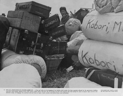 Nisei girl looking over the baggage of two families