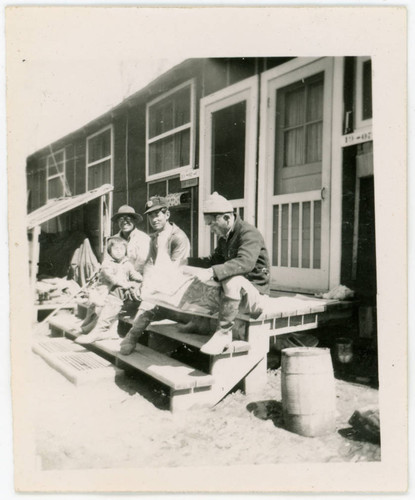 Men and young girl sitting on barrack stairs