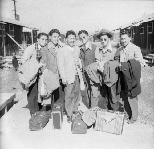 Group photograph of Nisei men with luggage in Jerome camp