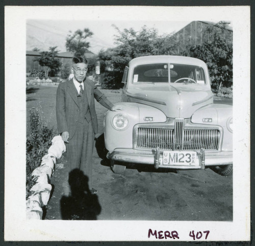 Photograph of an elderly man posing next to a car near the Manzanar hospital