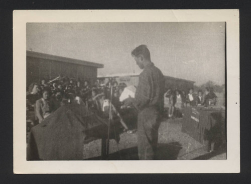 Man speaking at microphone in front of a group of young people