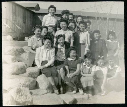 Photograph of a group of women and girls posing on the rocks next to the Manzanar hospital