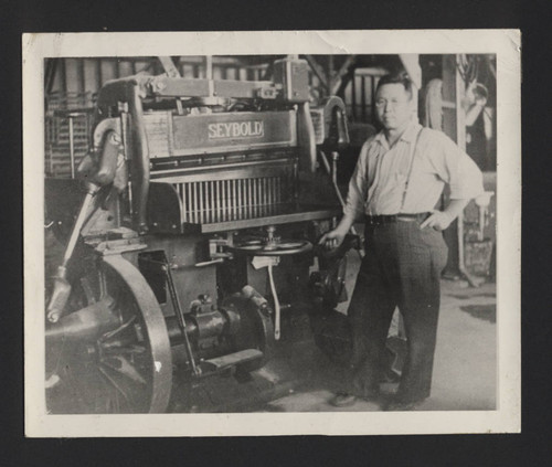 Photograph of man standing next to "Seybold" machine