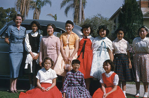 Women and children posing in front of car