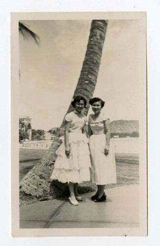 Two women standing by tree