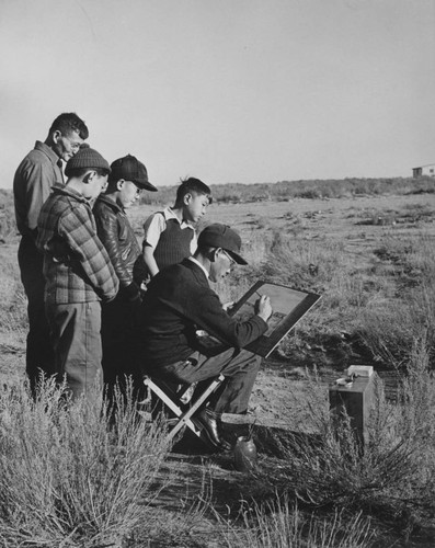 [Artist completing a watercolor at Granada incarceration camp]