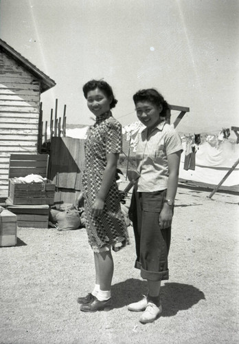 Two women posed outside, clothes line in background