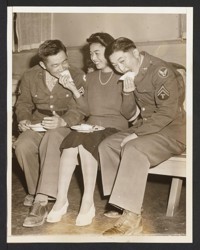 Home on Leave. Cpl. Frank N. Okimoto (left), formerly of Marysville, Calif.; Sachiko Higashi, Sacramento, Calif. (center), and Cpl. Tom Nakagawa, enjoy some refreshments served at a dancing party held at the Tulelake, Calif., Japanese Relocation Center. The two soldiers came to the camp on leave to visit their parents
