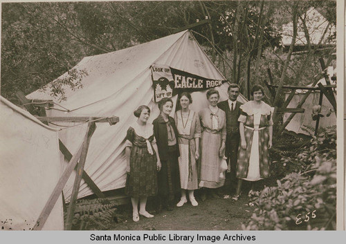 Young women and man stand in front of tent at Institute Camp, Temescal Canyon, Calif