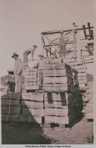 Carpenters and workmen pile lumber at Construction Center, Assembly Camp in Temescal Canyon, Pacific Palisades, Calif