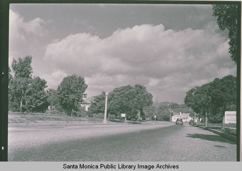 Automobile travels a wide boulevard in the Huntington Palisades