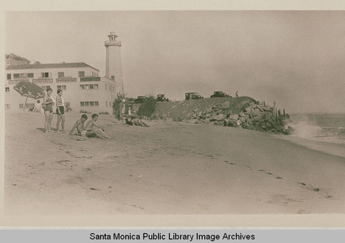 A few beachgoers near the lighthouse near the end point of Long Wharf at Potrero Canyon, Calif