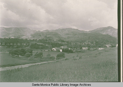 View of an open field and houses looking up Temescal Canyon and Haverford Avenue