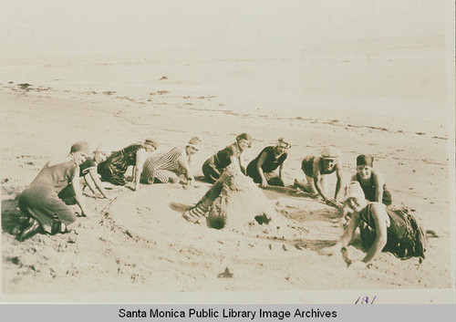 Girls in bathing suits build a sand castle on the beach near Pacific Palisades, Calif