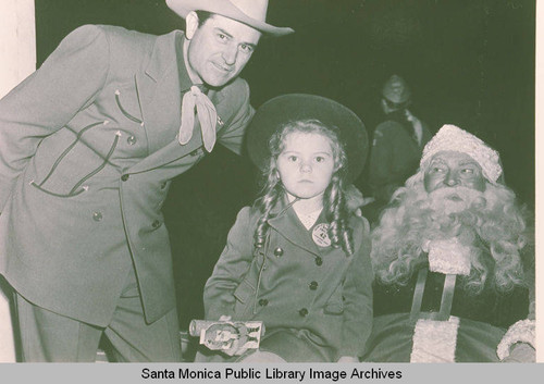 A man and a girl posing with Santa Claus in Pacific Palisades