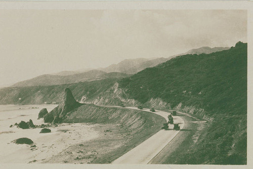 Automobiles speed by Castle Rock on Pacific Coast Highway