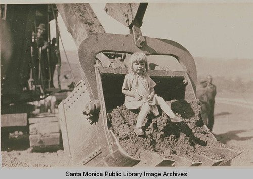 Dorothy Niedrich ("Mr. Niedrich's little daughter") sitting on a steam shovel at ceremonies marking the completion of grading on Beverly (Sunset) Blvd. from Los Angeles to Pacific Palisades, August 18, 1925