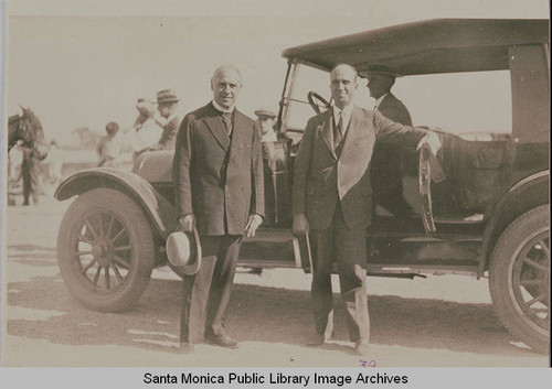 Bishop Charles Wesley Burns (on the left) and Reverend Charles Scott in front of a car at the ceremonies marking the completion of grading on Beverly (Sunset) Blvd. from Los Angeles to Pacific Palisades, August 18, 1925