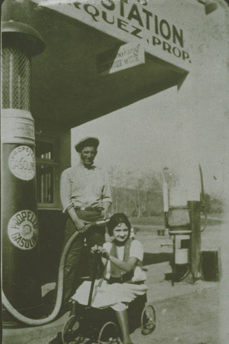 Tiny Marquez seated in a wagon in front of the Marquez Family's West End Service Station in Santa Monica Canyon