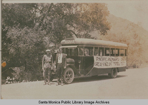 Mr. Clark (security guard for the Pacific Palisades Association) on the left and John Cadwallader (bus driver) on the right stand in front of the Pacific Palisades bus at the Assembly Camp, Temescal Canyon, Calif