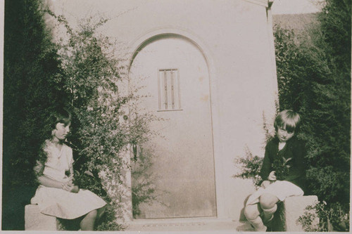 Jeannette Waite sits with another child outside a front door at 1058 Galloway Street in Pacific Palisades