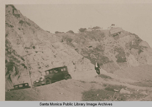 A man walking on the side of a road near Pacific Coast Highway at bottom of Potrero Canyon, Calif