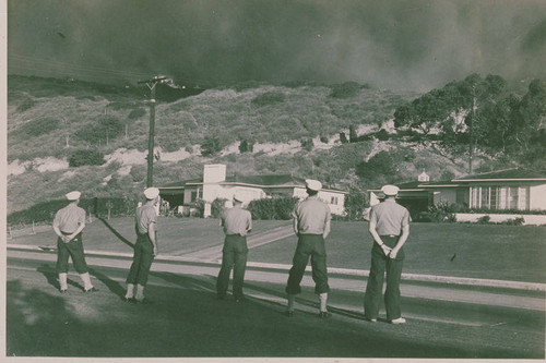 Firefighters lined up near a fire threatening homes in Pacific Palisades, Calif