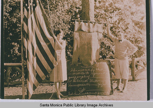 David Stratford and an unidentified woman raising the flag at the Institute Camp in Temescal Canyon, Calif