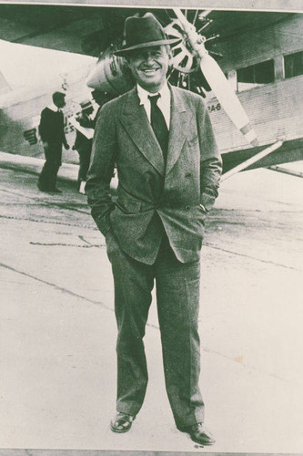 Will Rogers standing with a Ford Tri-Motor aircraft behind him