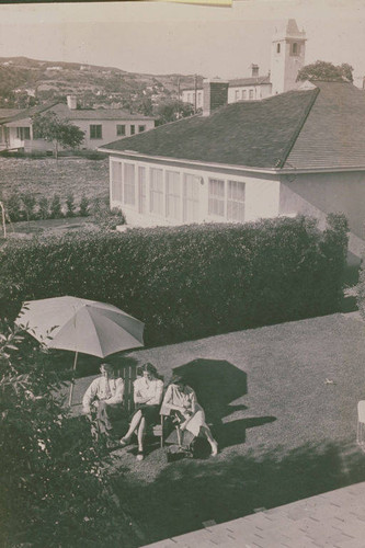 Clearwater family relaxing under an umbrella in their backyard, Pacific Palisades, Calif