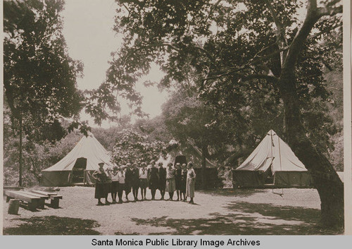 A group of young women campers join together for this photo in front of large tents at Institute Camp, Temescal Canyon, Calif