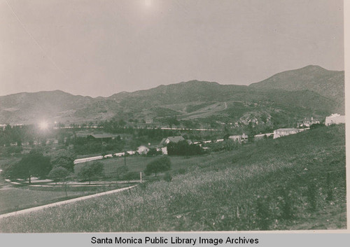 View of an open field and houses looking northwest up Temescal Canyon with Haverford Avenue to the right