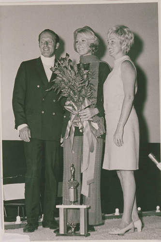 A woman receiving an award with a bouquet of flowers in her arms, Pacific Palisades, Calif