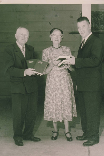 Robert Norris (left) and his wife are presented with copies of a hymnal