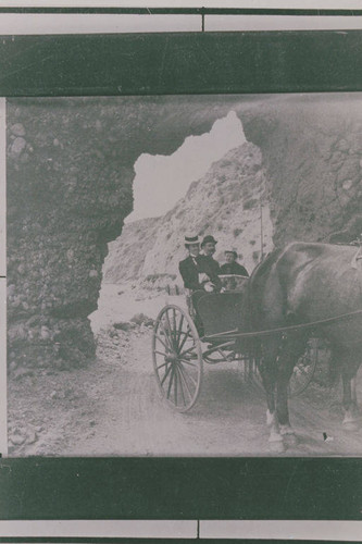 Wagon carrying passengers through Arch Rock, south of Topanga Canyon, Calif