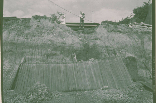 A man holding a child standing atop a bluff damaged by landslide