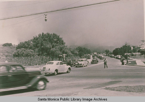 Cars are backed up on Sunset Blvd. in Pacific Palisades, with smoke in the distant sky from a fire