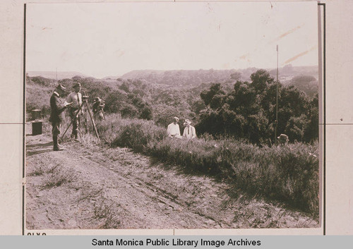 Surveyor crew looking down Temescal Canyon, Pacific Palisades, Calif. to the ocean where Aldersgate Lodge is today with the manager of the construction site, Clark Standiford at far right