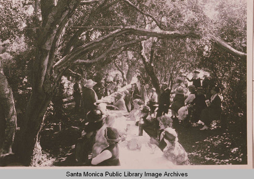 Women in fashionable hats at a picnic gathering under the oaks in Temescal Canyon, Pacific Palisades, Calif