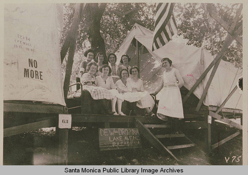 Young women pose together at their tents with a sign "Dew-Drop Inn" at the Institute Camp in Temescal Canyon, Calif